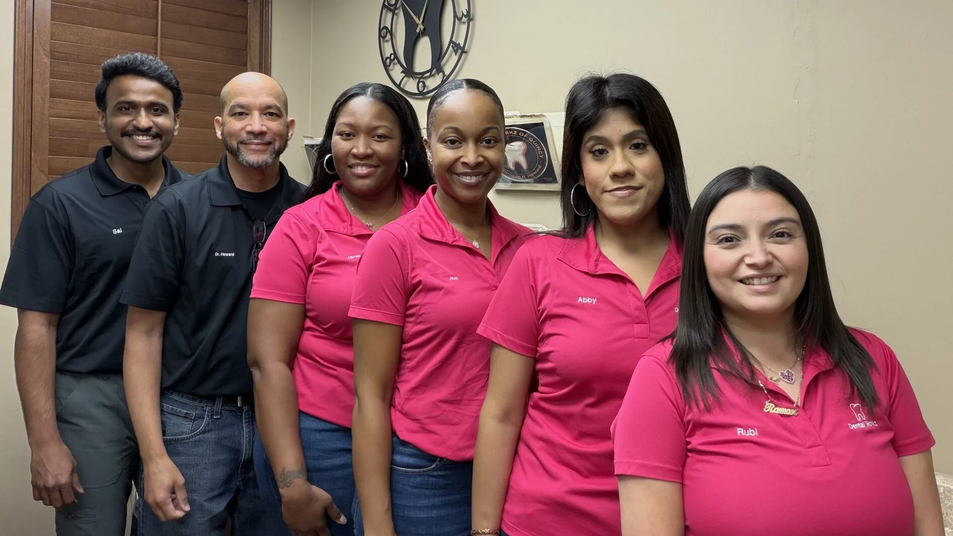 Full Dental Workz team photo featuring Sai, Dr. Howard, Jare, JoJo, Abby, and Rubi standing in front of the office tooth clock